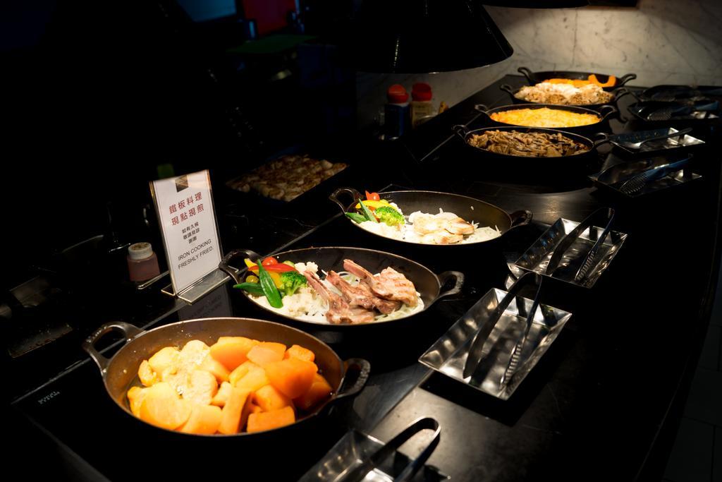 Ambassador Hotel Kaohsiung Exterior photo The photo shows a buffet-style food display featuring several dishes in oval serving pots. There are a variety of cooked vegetables and meats, with one pot containing a mix of root vegetables or squash, another with meat and vegetables, and possibly 