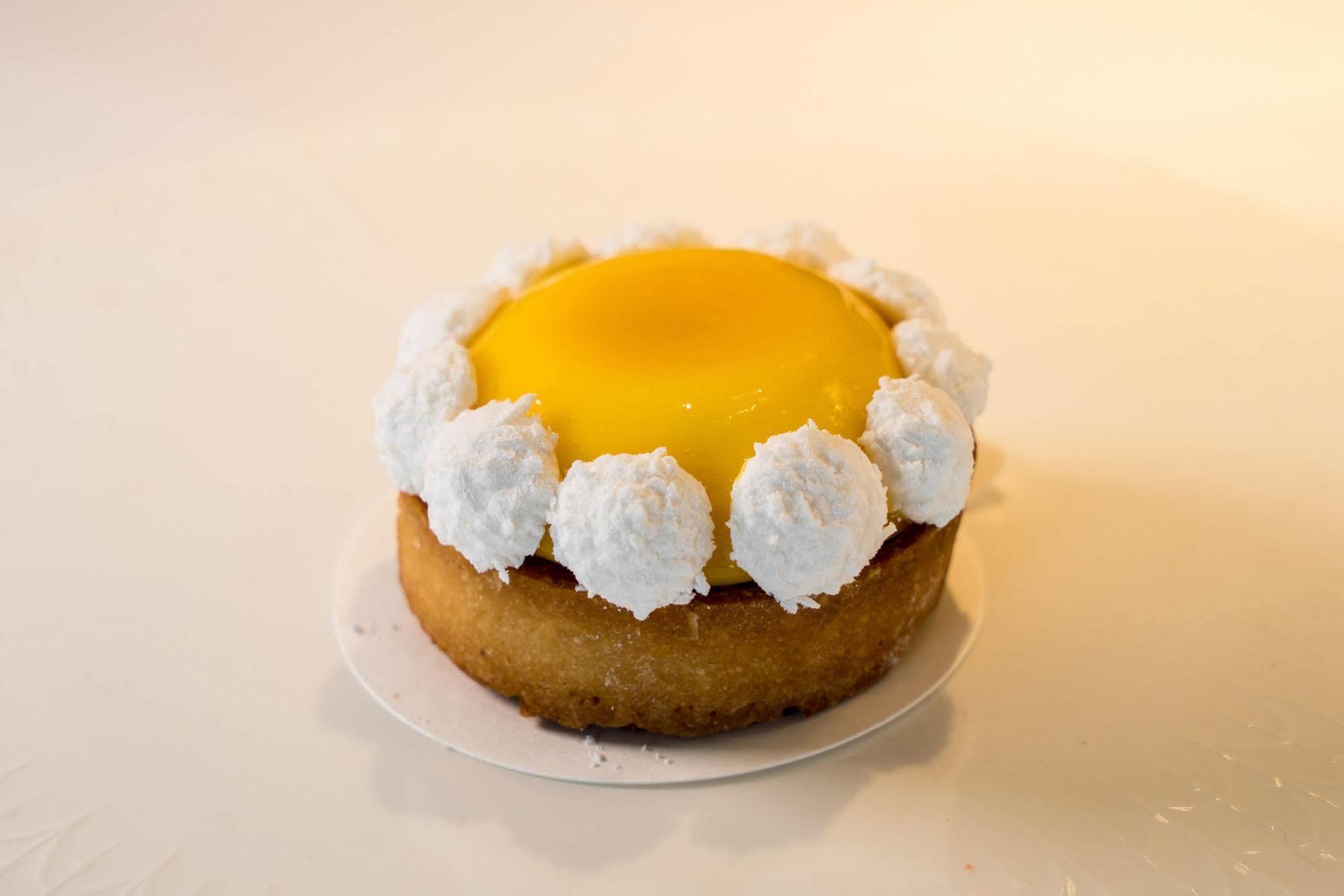 Ambassador Hotel Kaohsiung Exterior photo The photo showcases a round dessert, likely a tart or mini cake. The base appears to be a golden-brown, crumbly crust. It is topped with a bright yellow custard or gel-like layer, which gives it a vibrant appearance. Surrounding the yellow center is 